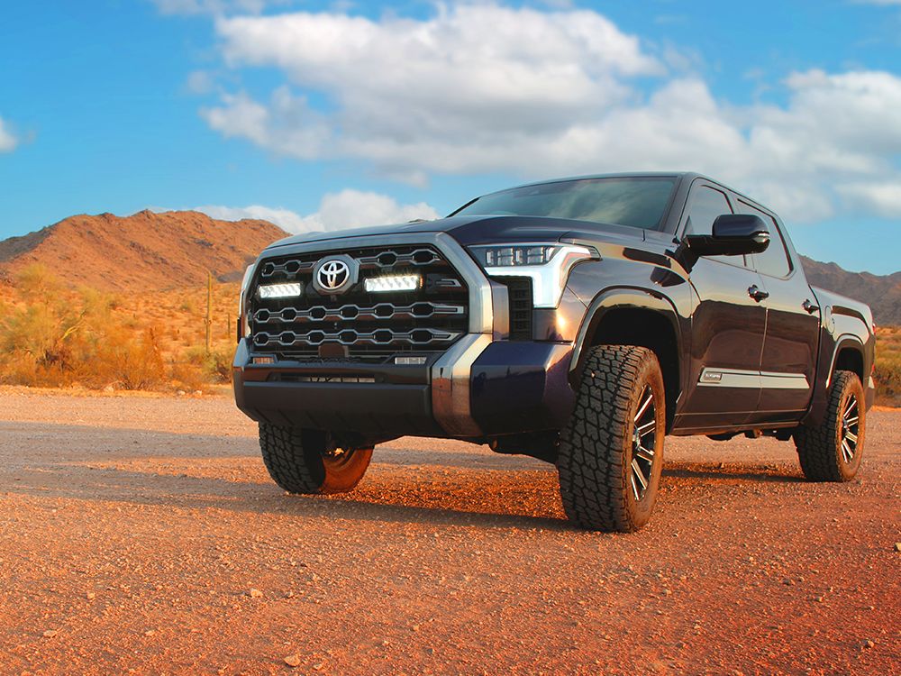 Toyota truck on a dirt road with mountains in the background with Lazer Lamps Grille Kit – Toyota Tundra Platinum (2022+)