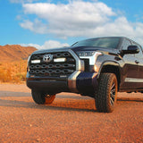 Toyota truck on a dirt road with mountains in the background with Lazer Lamps Grille Kit – Toyota Tundra Platinum (2022+)