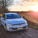 White Volkswagen car on a rural road with sunset in the background