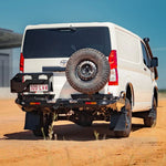 White van with a spare tire mounted on the back, parked on a dirt road.