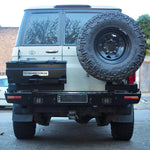 Back view of a white Toyota Land Cruiser with a spare tire mounted on the back, parked on a street.