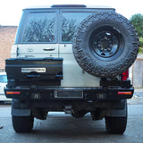Back view of a white Toyota Land Cruiser with a spare tire mounted on the back, parked on a street.