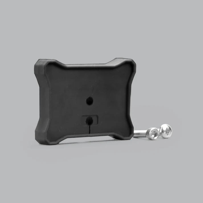Black moulded flat mount for a rock light seen at an angle, the ribbed rear face with a cable hole and a slotted opening, with two stainless button-head screws laid beside it