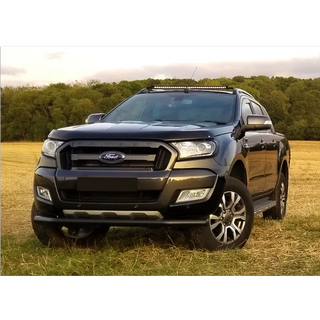 Black Ford parked in a field with trees in the background with Lazer Lamps Roof Mount Kit – Ford Ranger (2016–2022 with Roof Rails)
