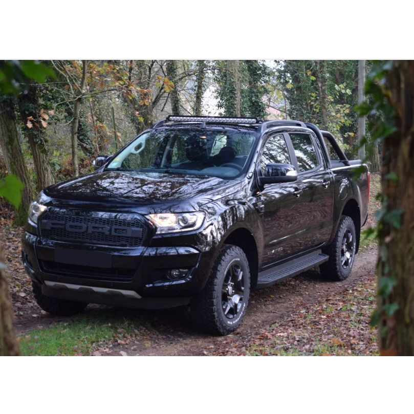 Black pickup truck parked in a forested area with Lazer Lamps Roof Mount Kit – Ford Ranger (2016–2022 with Roof Rails)