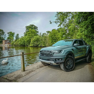 Green ford ranger raptor parked by a river with trees in the background with Lazer Lamps Grille Kit – Ford Ranger Raptor (2018–2022)
