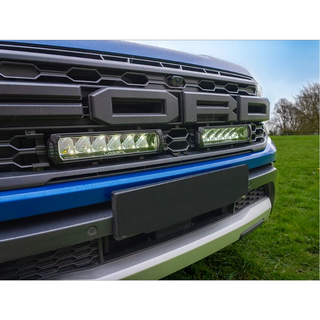 Close-up of a Ford truck grille with LED lights on a grassy background