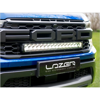 Close-up of a Ford vehicle grille with LazerLamps Raptor Grille Kit, on a grassy background.