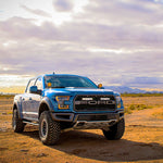 Blue Ford truck on a desert road with a cloudy sky