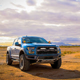 Blue Ford truck on a desert road with a cloudy sky