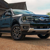 Ford truck parked in front of a wooden building with trees in the background