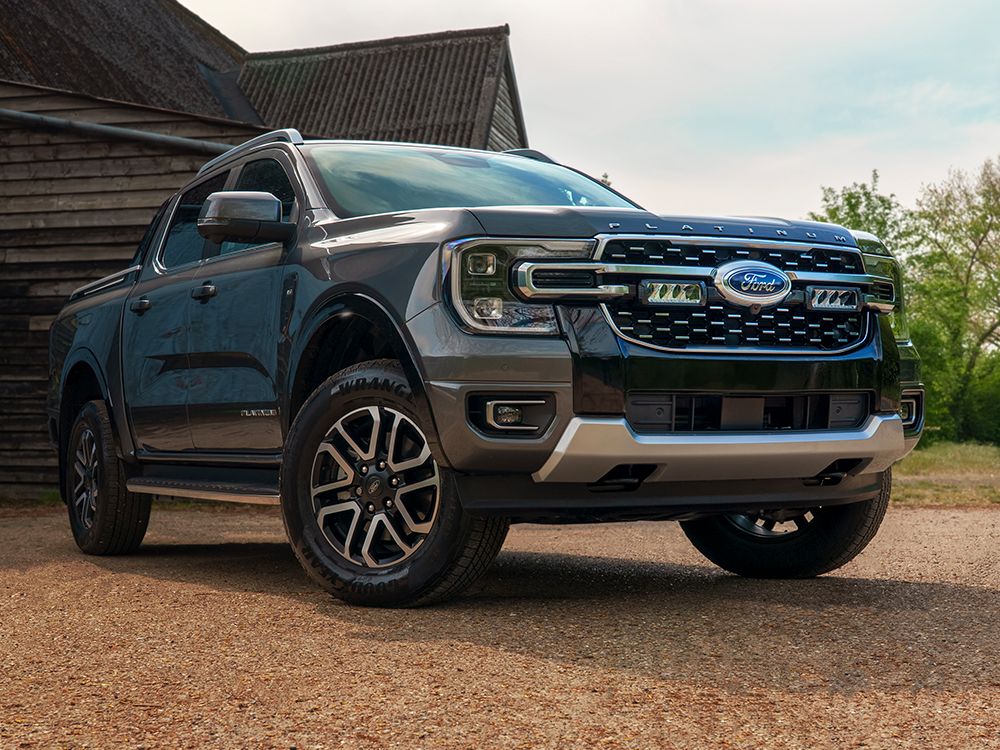 Ford truck parked in front of a wooden building with trees in the background