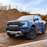 Blue Ford truck on a dirt road with a clear sky