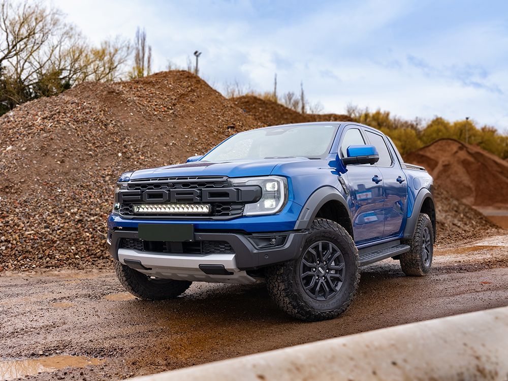 Blue Ford truck on a dirt road with a clear sky