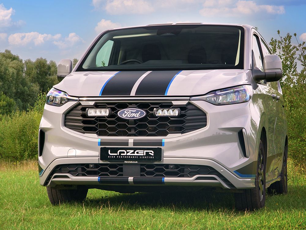 White Ford Transit van with black and blue stripes on a grassy field