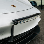 Close-up of a car's front bumper with a Lazerlamps Licence Plate Mount (Glide) on a white car.