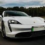 White Porsche electric car on a track with trees in the background