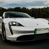 White Porsche electric car on a track with trees in the background