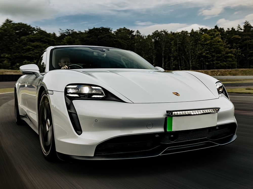White Porsche electric car on a track with trees in the background