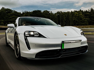 White Porsche electric car on a track with trees in the background