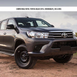Gray Toyota Hilux pickup truck on a dirt road with a cloudy sky in the background.