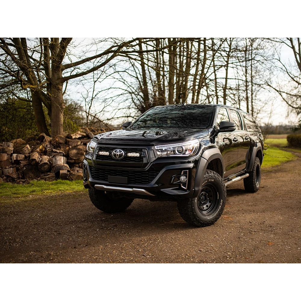 Black Toyota SUV parked on a dirt road with trees in the background