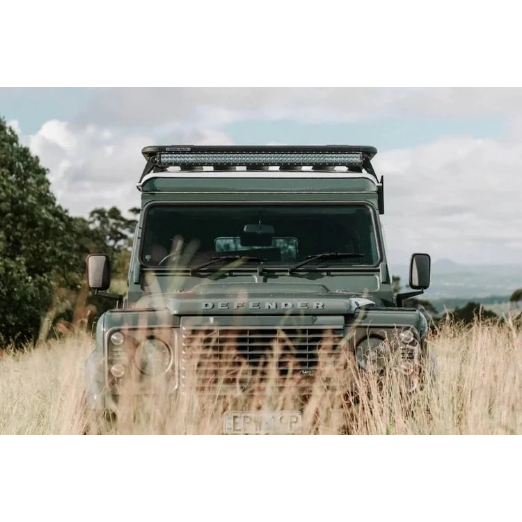 Land Rover Defender in a grassy field with a clear sky – Headspace Roof Conversion D90/110