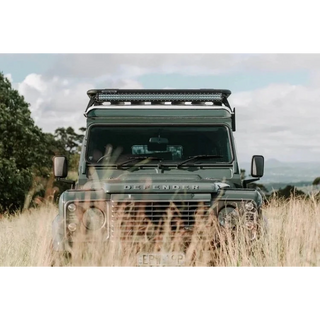 Land Rover Defender in a grassy field with a clear sky – Headspace Roof Conversion D90/110