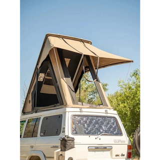 White SUV with a beige rooftop tent set against a clear blue sky – Headspace Roof Conversion LC60