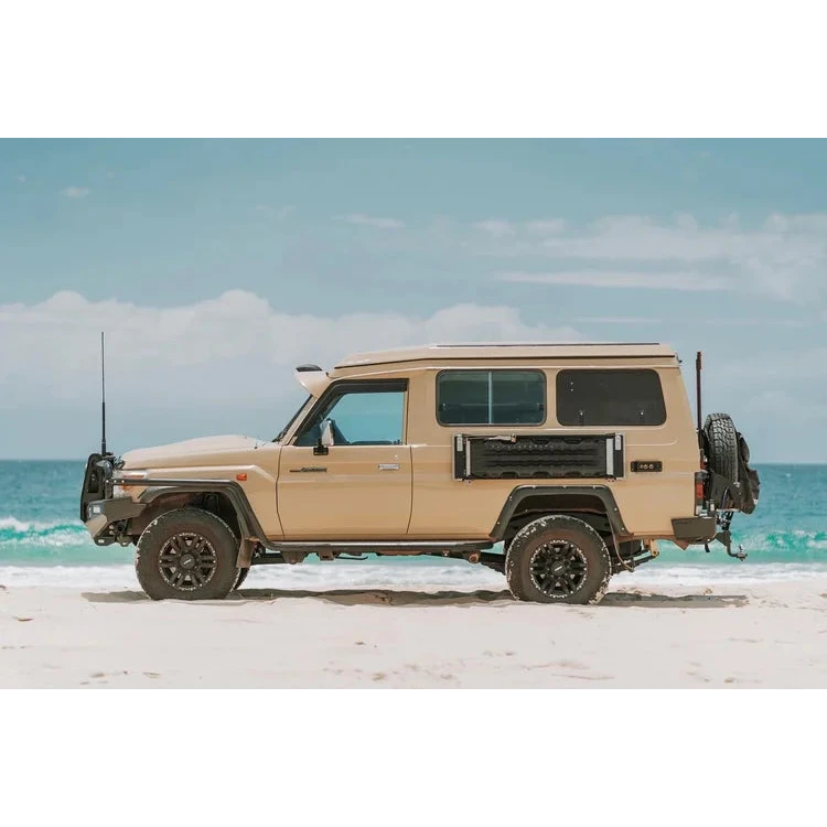 Beige off-road vehicle with a camper shell on a sandy beach with ocean and sky in the background – Headspace Roof conversion LC75/78