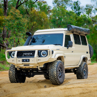 Beige 78 Series Troopy with the Headspace roof conversion closed, on a forest track