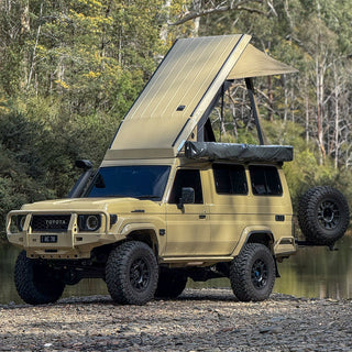 Beige 78 Series Troopy with the Headspace roof raised, parked near water