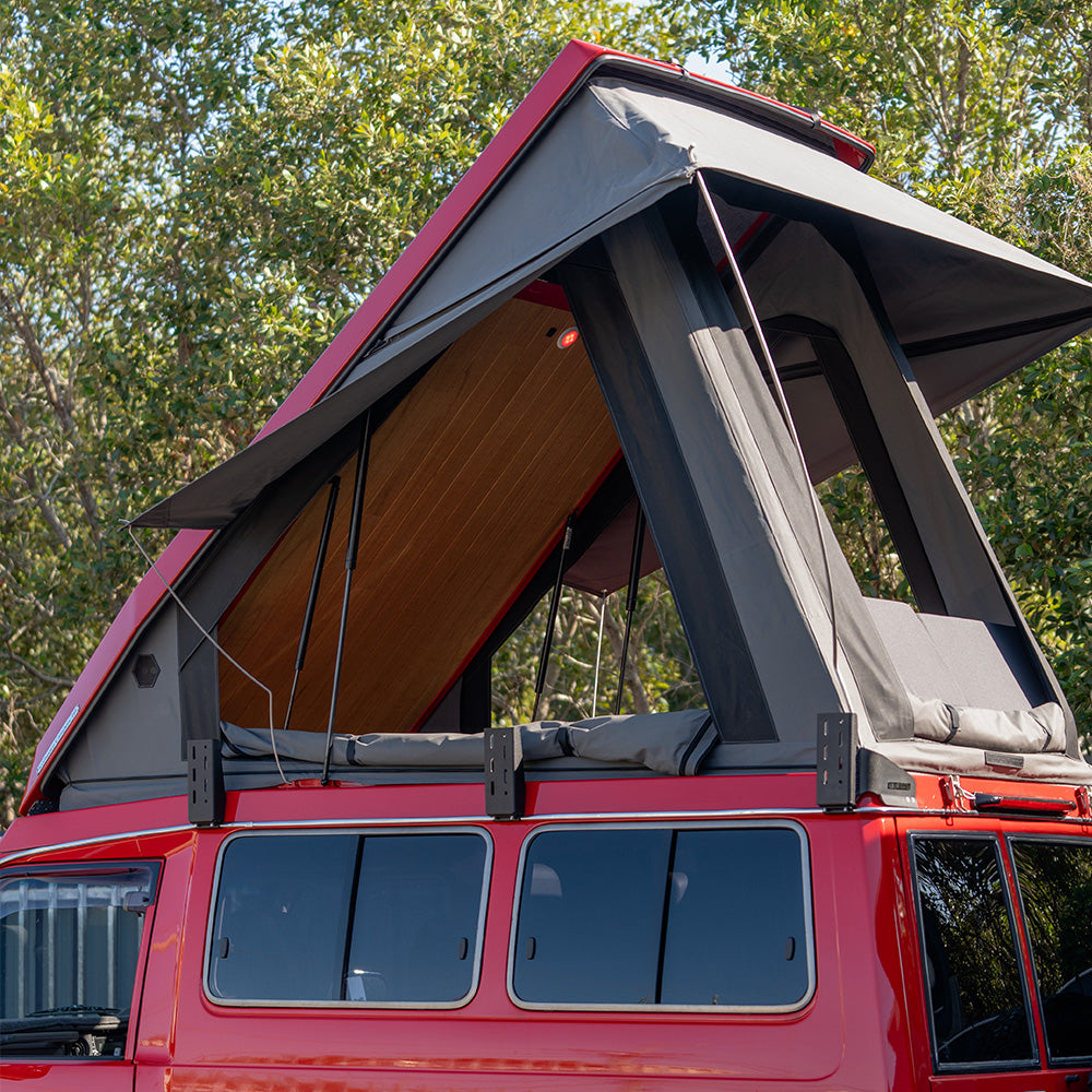 Red Troopy with the Headspace roof conversion raised against a forest background