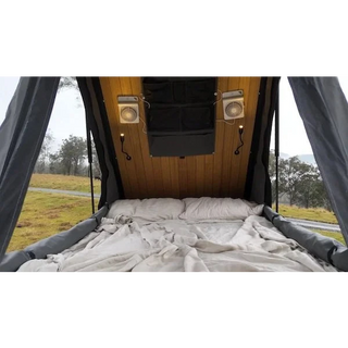 Bed inside a camper van with wooden paneling and curtains, outdoors – Headspace Roof Conversion LC76
