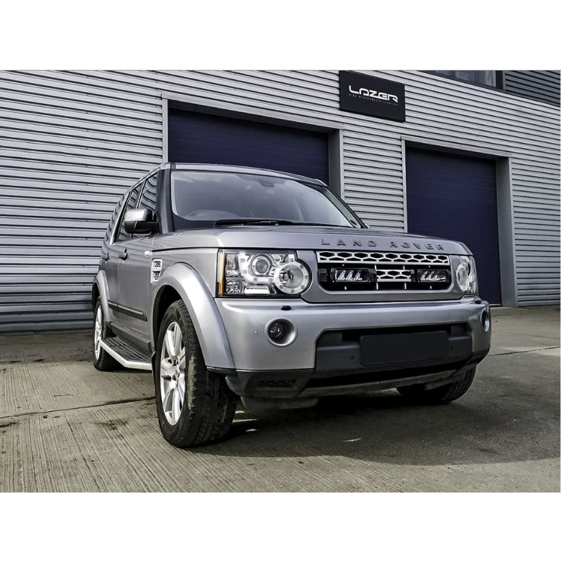 Silver Land Rover parked in front of a building with 'Latan' branding.