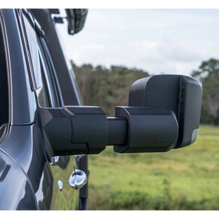 Side view of a vehicle with extended towing mirrors in an outdoor setting.