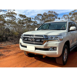 White Toyota SUV on a dirt road with trees in the background