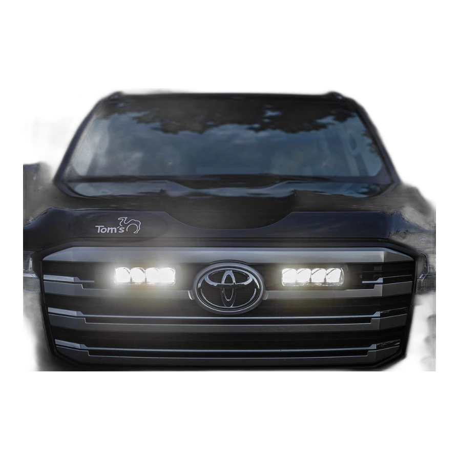 Close-up of a Toyota vehicle's front grille with illuminated headlights and Lazer Lamps Grille Kit – Toyota Land Cruiser 300 Series (2022+)