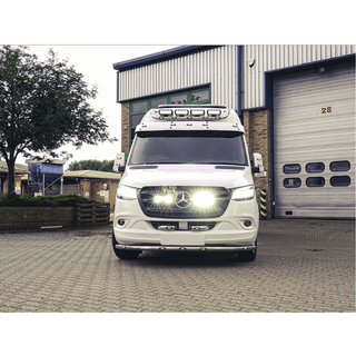 White Mercedes-Benz van parked in front of a building with a garage door with Lazer Lamps Mercedes Sprinter (2018+) Grille Kit