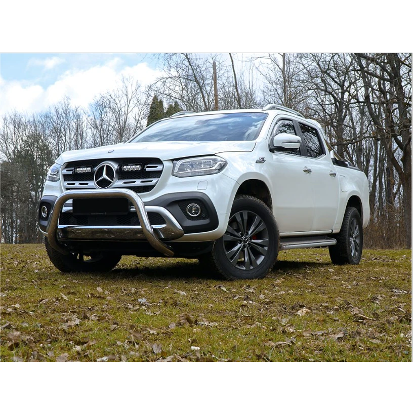 White Mercedes-Benz truck on a grassy field with trees in the background