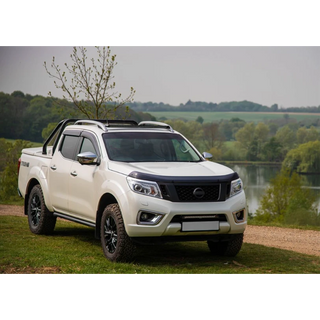 White Nissan pickup truck parked by a lake with trees in the background with Lazer Lamps Nissan Navara (2014-2019) Roof Mounting Kit