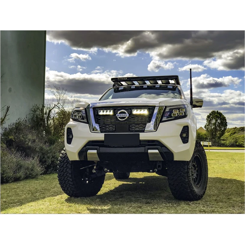 White Nissan truck on a grassy area with a cloudy sky