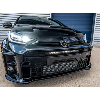 Black Toyota car with a prominent grille and headlights in front of a garage door.