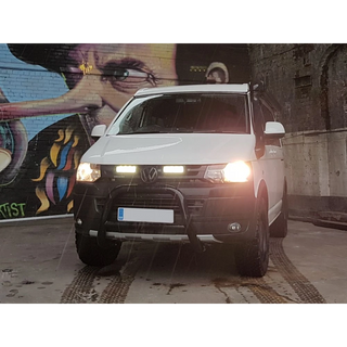 White Volkswagen van with headlights on in front of a colorful mural with Lazer Lamps Grille Kit for Volkswagen T5.1