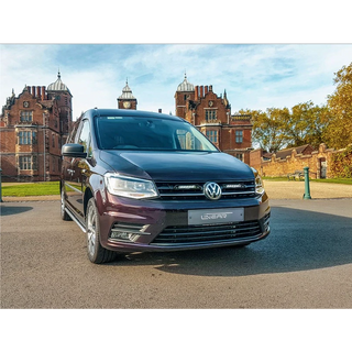 Volkswagen van parked in front of a historic building with trees in the background