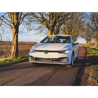White Volkswagen car on a rural road with trees and fields in the background with Lazer Lamps Grille Kit for VW Golf MK8 (2020–2024)