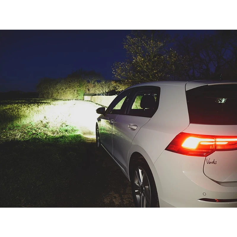 White car parked on a grassy area at night with visible brand logo.