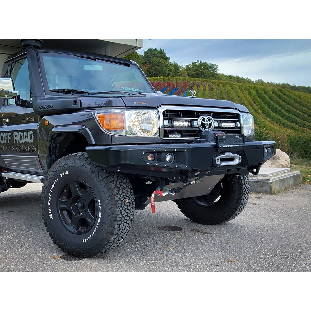 Black Toyota Land Cruiser off-road vehicle with large tires and Lazer Lamps Grille Mount Kit for Toyota LandCruiser 70 Series ST4 Evo on a paved surface.