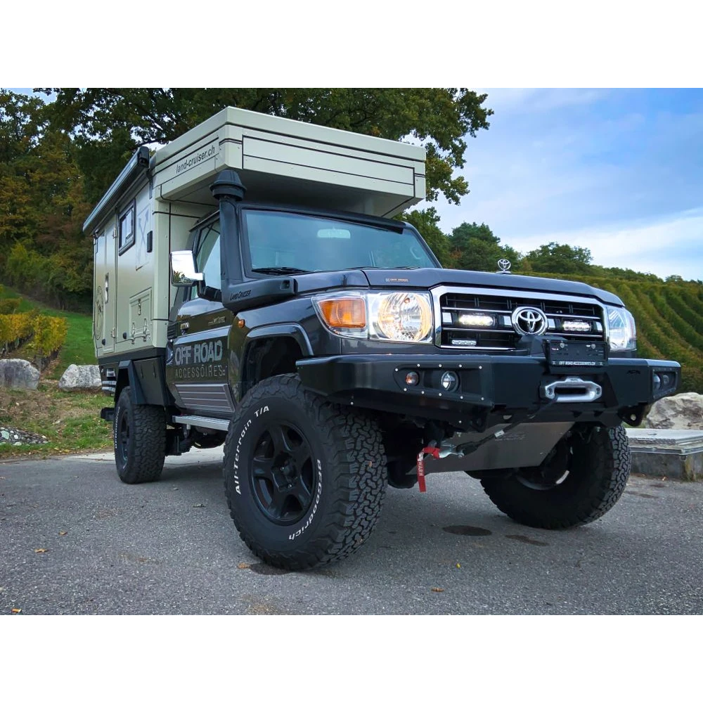 Toyota truck with a camper shell parked on a road with trees in the background