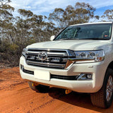 White Toyota SUV on a dirt road with trees in the background